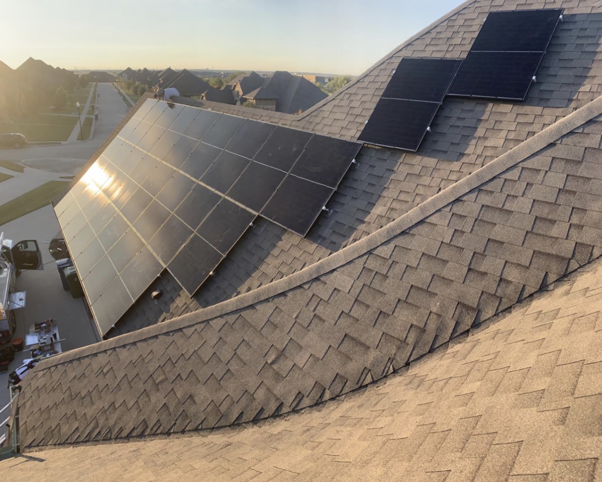 Crew setting solar panels on a shingle roof